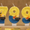 Three yellow construction excavator birthday cake candles with blue glitter bases