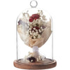 A glass dome cloche with a floral arrangement displayed on a wooden base.