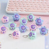 A collection of mini rock-paper-scissors themed keychains in purple, blue, and green are displayed on a white grid background