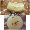 Two yellow squishy toys shaped like a banana bear with a simple face, packaged in clear plastic.