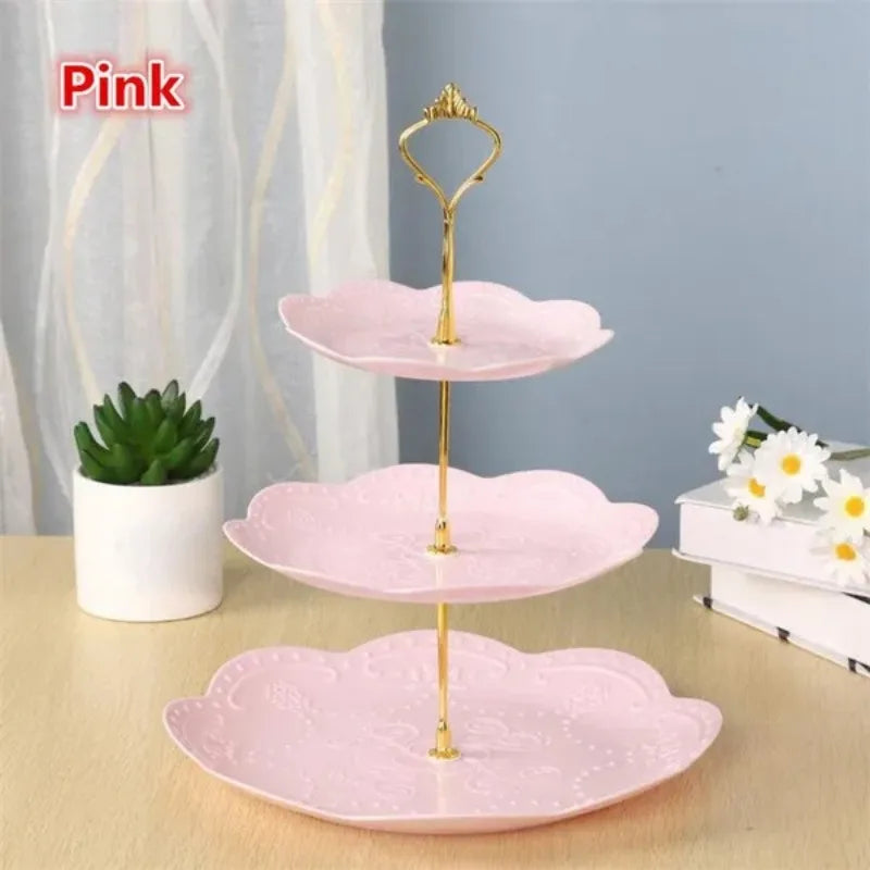 A pink three-tier detachable cake stand for desserts and fruit with gold accents.