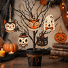 A set of vintage wooden Halloween hanging ornaments featuring owls, bats, skulls, and cats displayed on a dark branch.