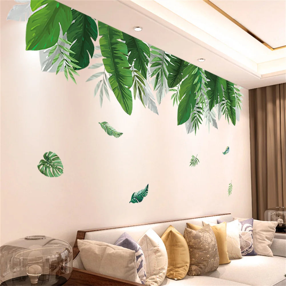 Green tropical leaf wall stickers decorating a white wall above a sofa.