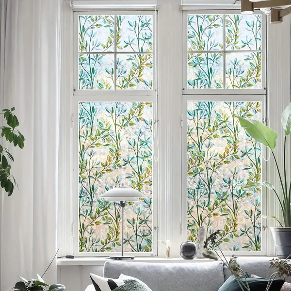 A window with green and blue stained glass privacy film covering the view of a plant indoors.