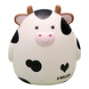 A cute white and black cow-faced piggy bank with pink nose and brown horns.