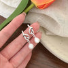 Elegant gold bean spliced pearl drop earrings displayed on a hand next to a flower and linen fabric.