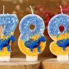Three birthday candles shaped like the number 789 made of blue and orange glitter on white wax sticks.