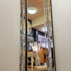 A tall silver crystal beveled wall mirror reflecting an interior space.
