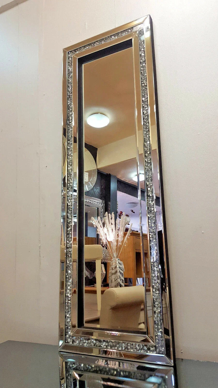 A tall silver crystal beveled wall mirror reflecting an interior space.
