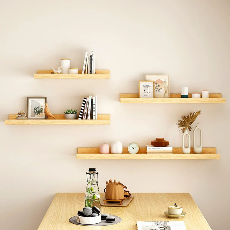 A display of natural wood floating shelves mounted on a light beige wall.