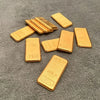 A set of ten simulated gold ingot fortune charms arranged on a dark gray surface.
