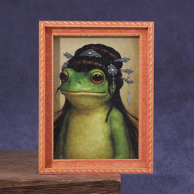 A framed picture of a green frog with decorative silver hair accessories.