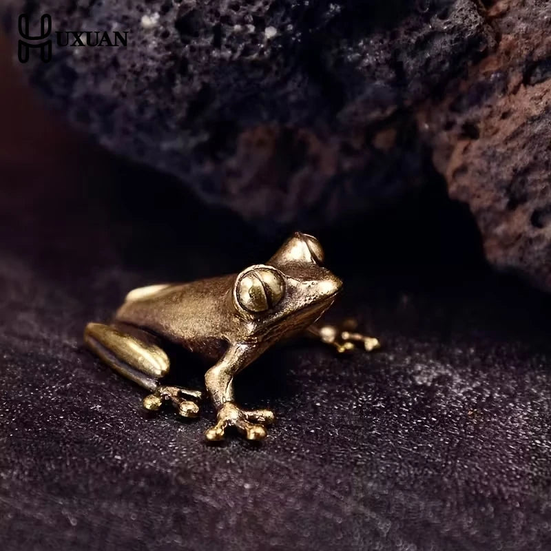 A vintage brass frog statue desktop ornament resting on a dark surface.