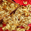A pile of gold silk rose petals in a woven basket and scattered on red fabric.