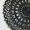 Decoración de pared colgante de madera negra con mandala intrincada y patrones remolino.