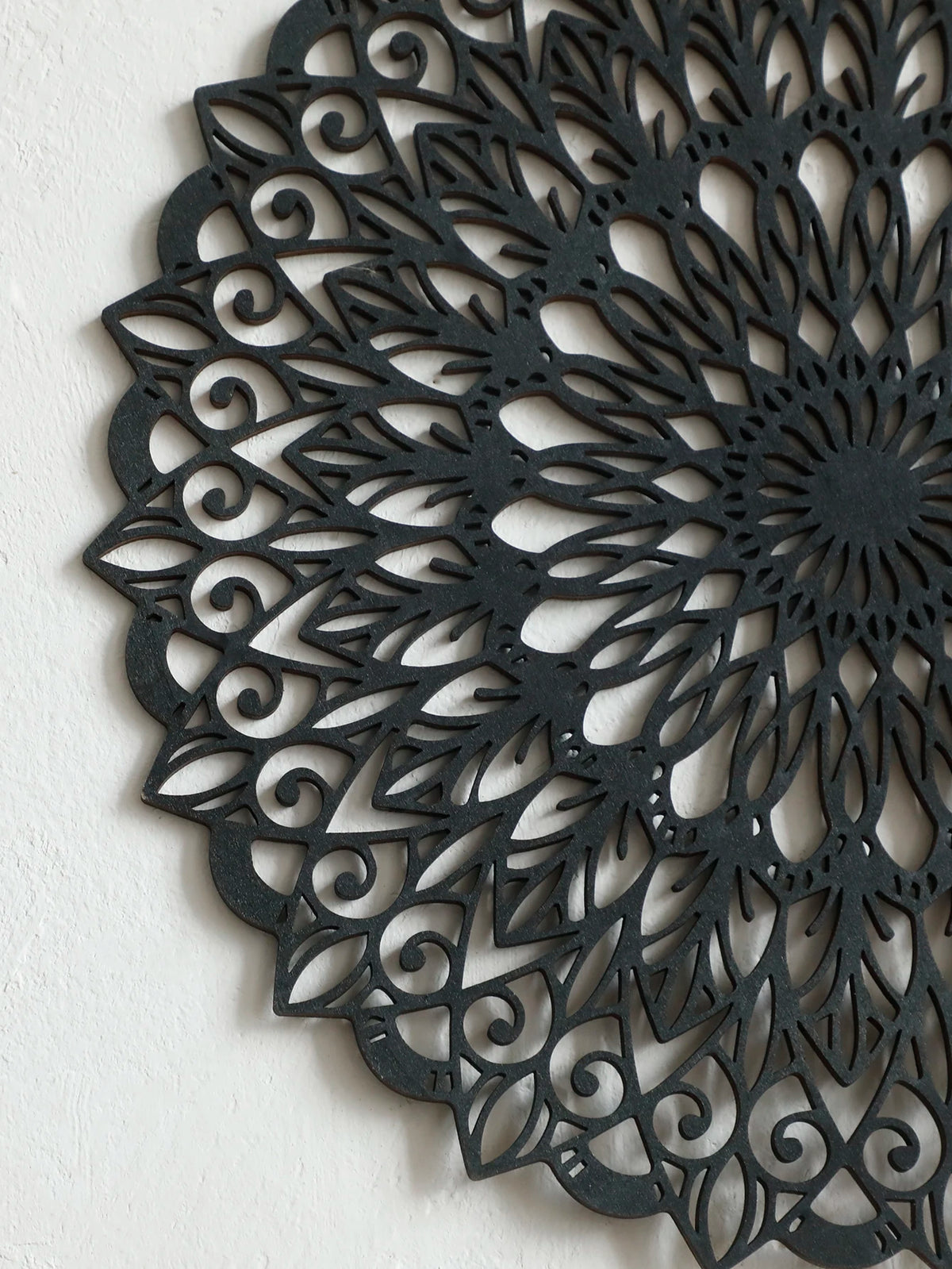 Decoración de pared colgante de madera negra con mandala intrincada y patrones remolino.