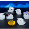 A set of seven white luminous ghost resin ornaments, including a purple hat ornament and a yellow pumpkin, displayed on a dar