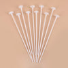 A collection of white macaron balloon sticks with holder cups arranged diagonally on a beige background.