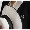 Close-up of white textured fabric and black fabric with pearl and rhinestone buttons on a garment
