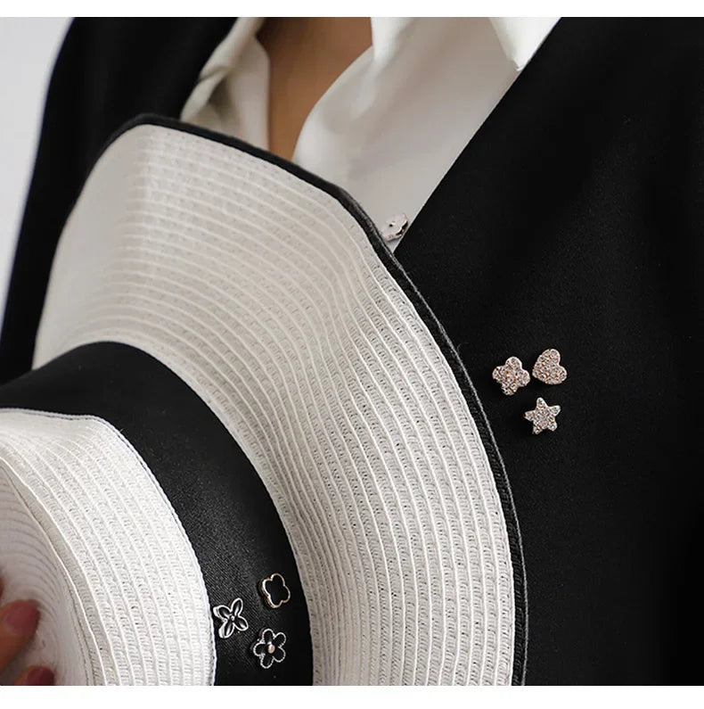 Close-up of white textured fabric and black fabric with pearl and rhinestone buttons on a garment