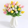 A bouquet of artificial tulip flowers in shades of pink, yellow, and white arranged in a white vase.