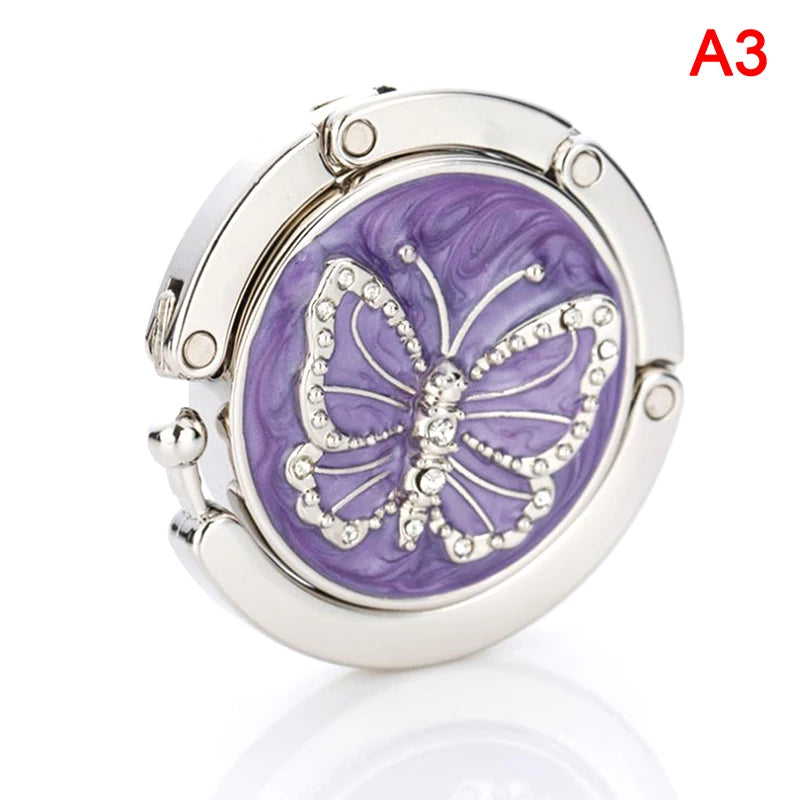 Silver foldable handbag hook with a purple marbled design and a butterfly motif