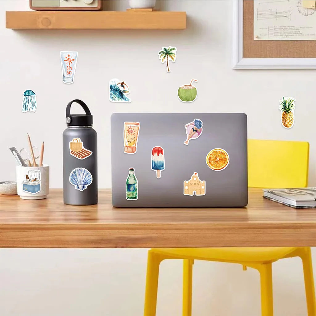 A laptop displaying a summer graffiti sticker pack featuring tropical fruits and sea life, placed on a wooden desk.
