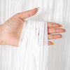A hand is holding and displaying metallic tinsel foil fringe curtain fabric.