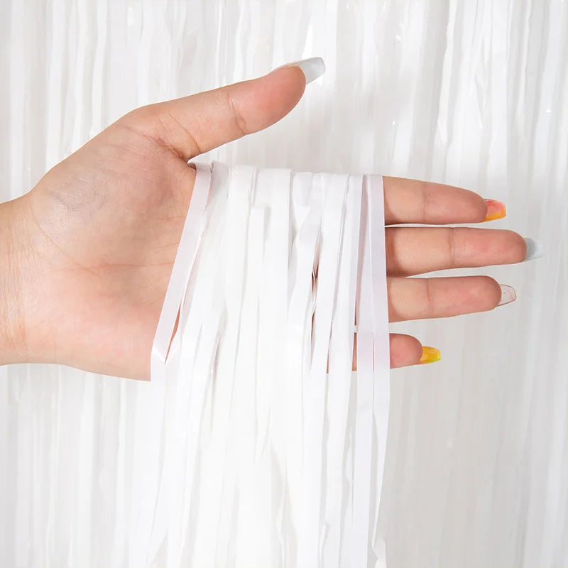 A hand is holding and displaying metallic tinsel foil fringe curtain fabric.