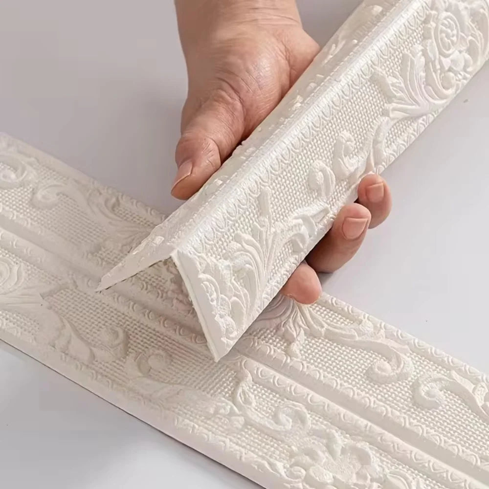 A hand holds a white self-adhesive PVC corner trim with a 3D textured edge, showing its decorative pattern.