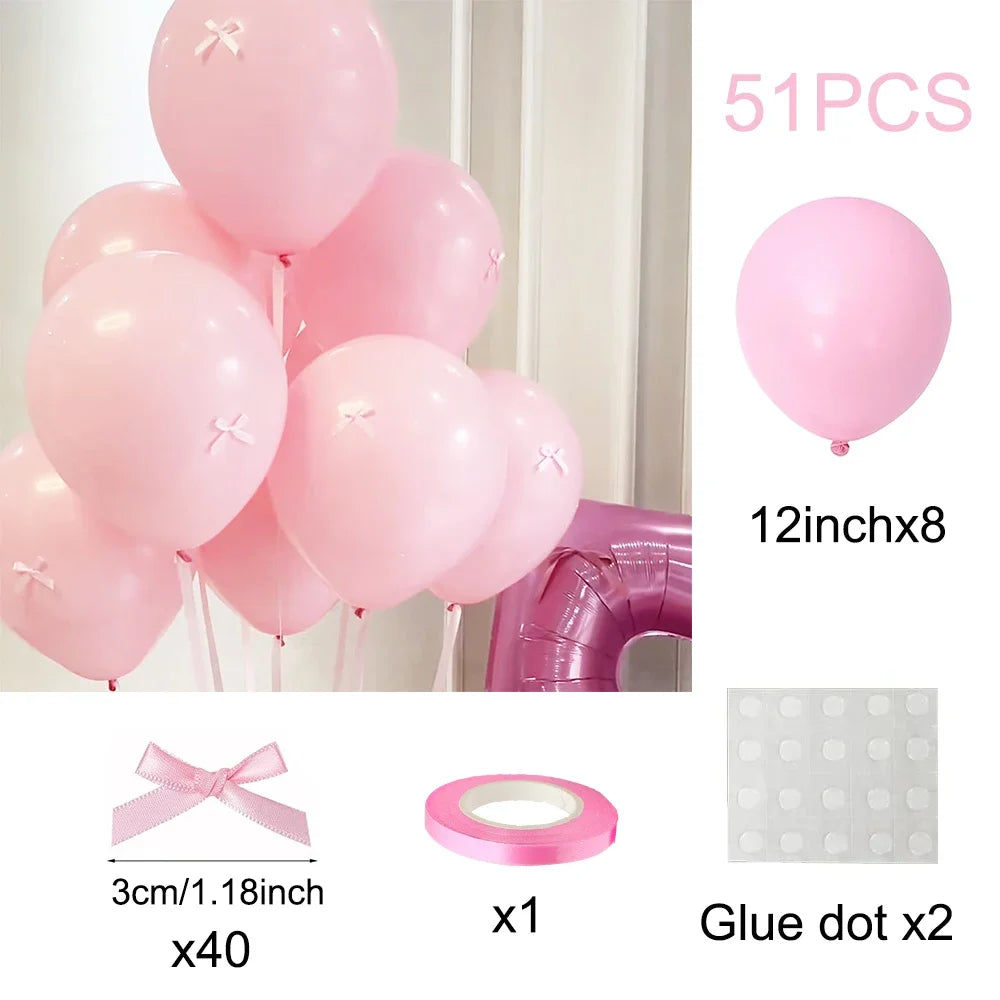 Pink latex balloons and accessories including a bow, a ring, and glue dots for decoration