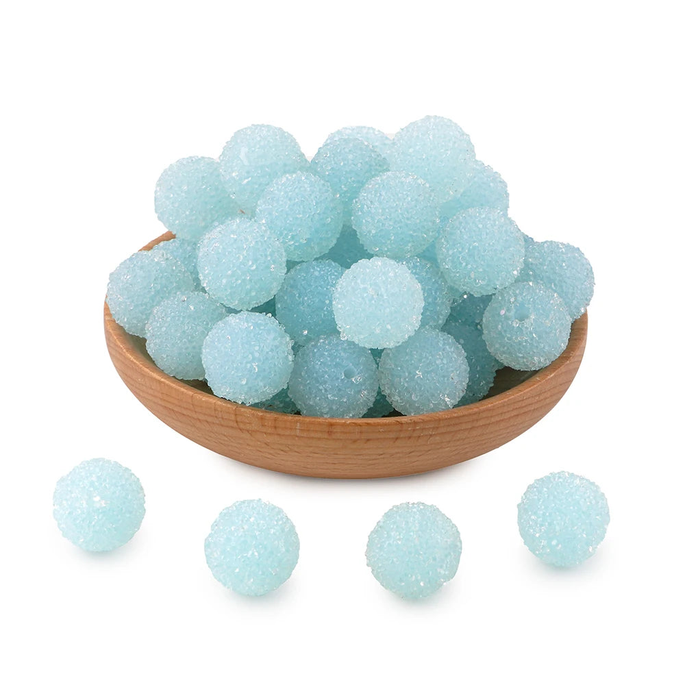 A pile of light blue textured resin beads for jewelry making in a wooden bowl with several loose beads nearby.