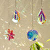 A collection of hanging crystal pendants, including teardrop and flower shapes, catching light against a soft background.