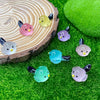A set of mini luminous resin bird fairy garden decor featuring various pastel colored birds on a green textured surface.