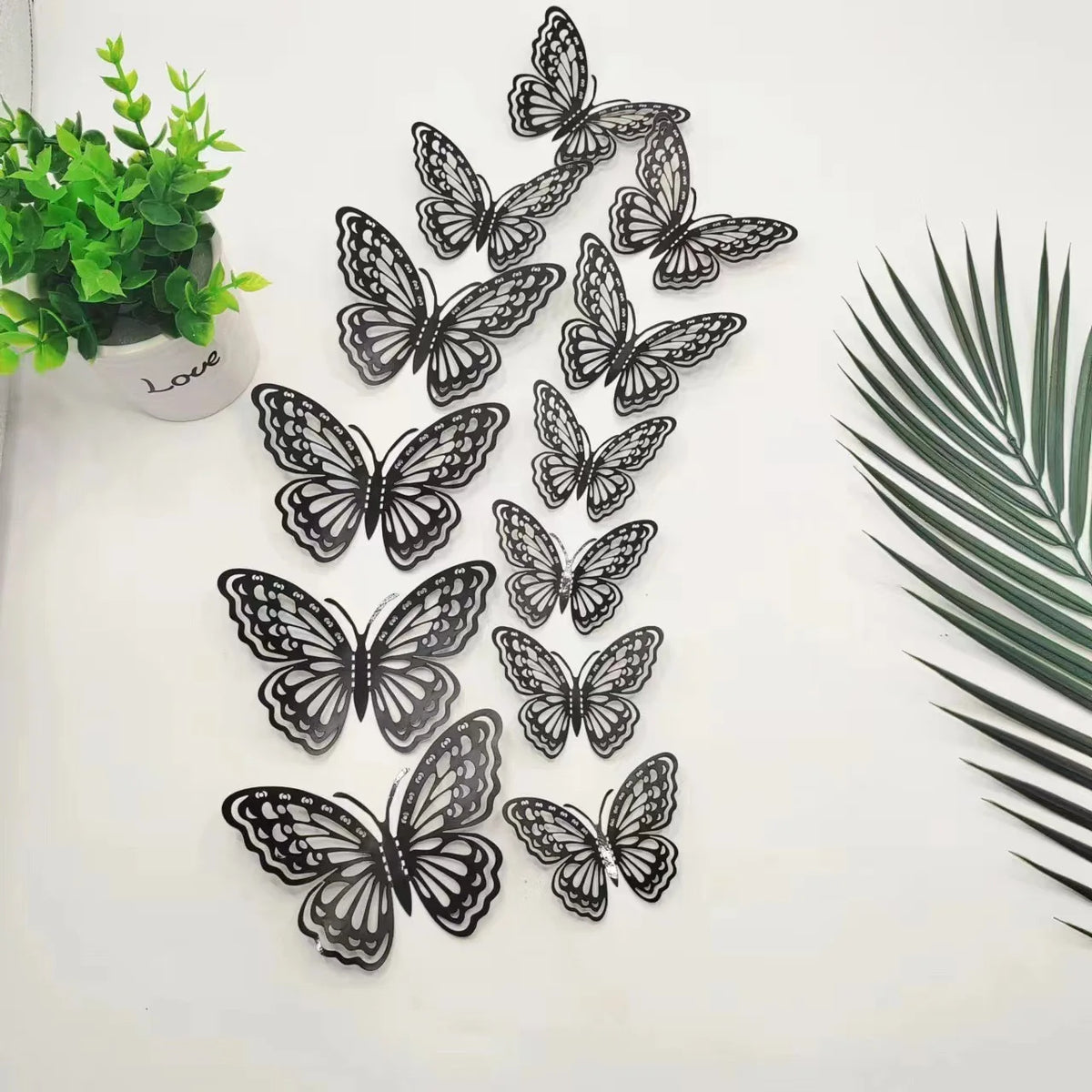 A collection of twelve black and white butterfly wall stickers arranged in a vertical pattern on a white background.
