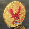 A gold collectible coin featuring a red mythical bird with outstretched wings and a Tai Chi motif.