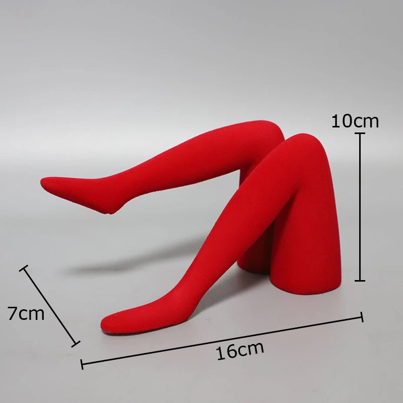 A red resin art sculpture of a human leg in a bent position, showing its dimensions.