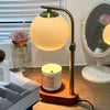 A brass aromatherapy wax melting lamp with a glowing spherical bulb sits on a wooden base.