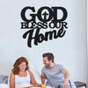 Un homme et une femme souriants regardent un panneau d'art mural qui dit 'Que Dieu bénisse notre maison'