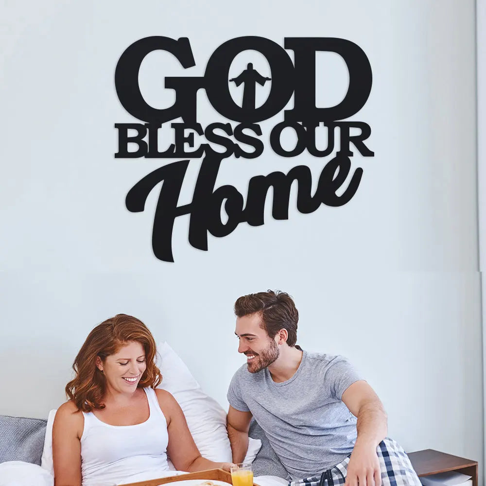 Un homme et une femme souriants regardent un panneau d'art mural qui dit 'Que Dieu bénisse notre maison'