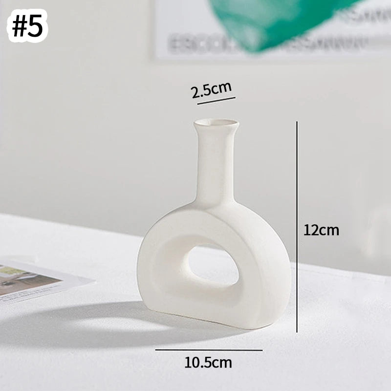 A white minimalist ceramic vase with a narrow neck and a wide, rounded base, shown in profile.