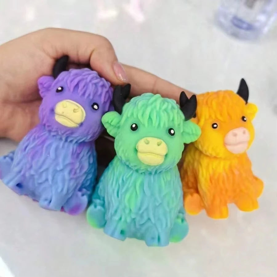 Three squishy toys shaped like Highland cows in purple, green, and orange colors