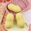 A yellow peanut-shaped stress ball is shown in a pink woven basket and on a light green tray.
