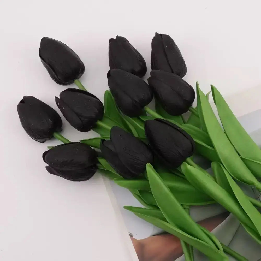 A bouquet of realistic artificial black tulips with green stems and leaves.