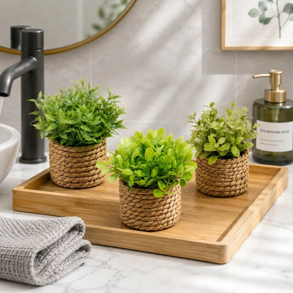 A potted artificial green plant in a woven basket sits on a wooden tray next to a kitchen faucet.