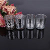 A set of silver glass votive candle holders with black geometric patterns displayed on a dark surface.