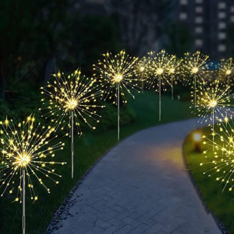 Une rangée de feux d'artifice solaires LED jaunes illuminant un chemin de jardin au crépuscule.