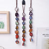 A set of natural crystal chakra rolling stone pendants hanging on a string.