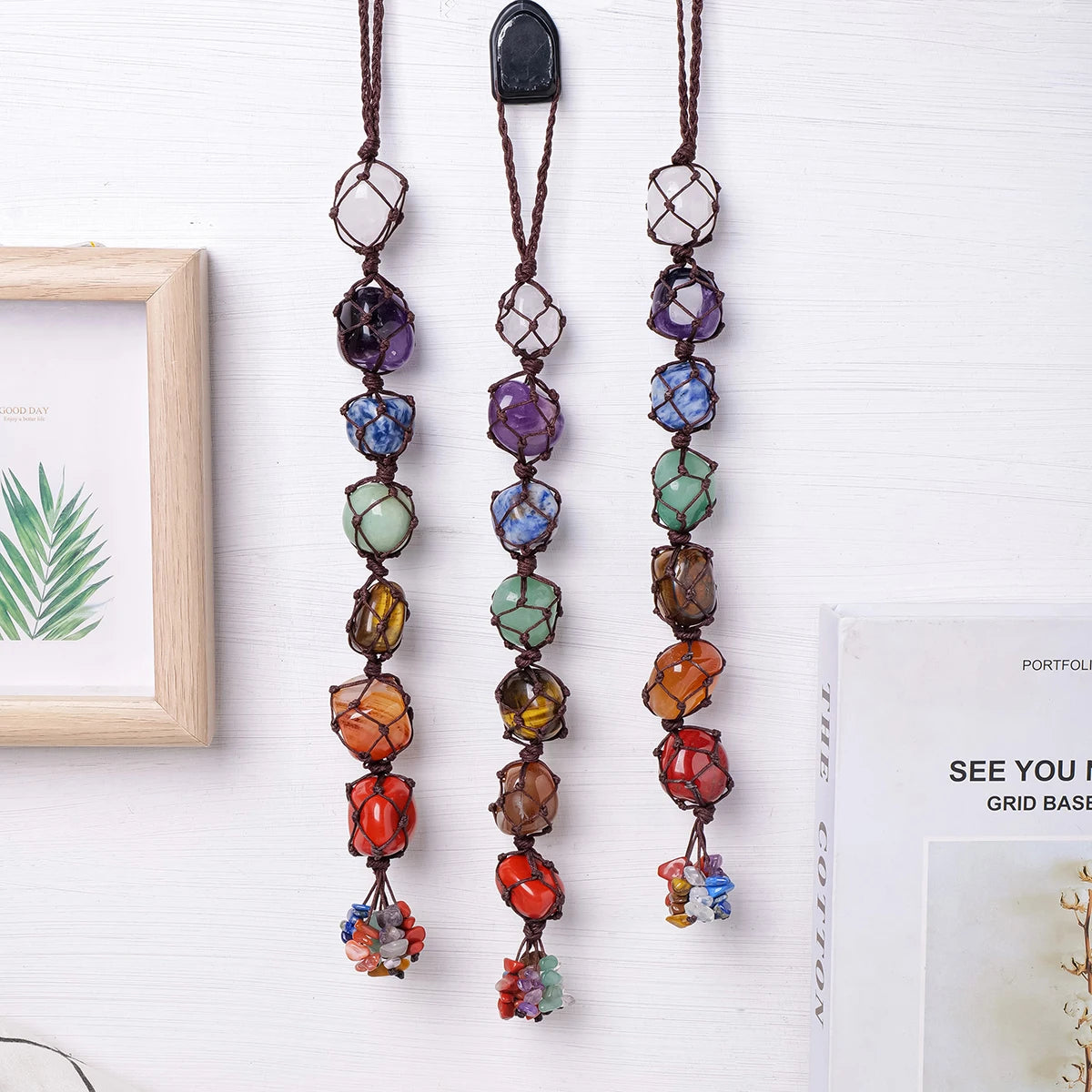 A set of natural crystal chakra rolling stone pendants hanging on a string.