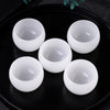 A set of white crystal agate healing bowls displayed on a black plate.